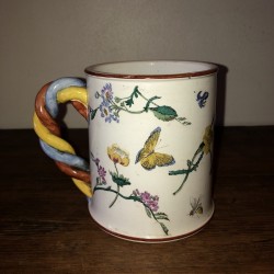 Old ceramic mug with twisted handle and floral decoration