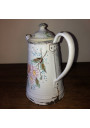 Old coffee maker in white enamelled sheet metal with floral decoration in relief