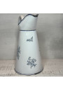 Old enamelled sheet metal pitcher with blue floral decoration on a white background