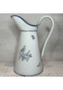 Old enamelled sheet metal pitcher with blue floral decoration on a white background