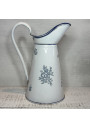 Old enamelled sheet metal pitcher with blue floral decoration on a white background