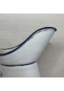Old enamelled sheet metal pitcher with blue floral decoration on a white background