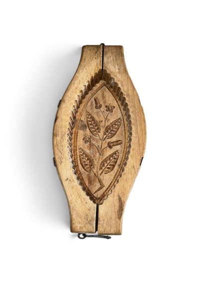 An antique wooden butter mold featuring a delicate floral pattern and carvings that evoke traditional, vintage kitchen charm.